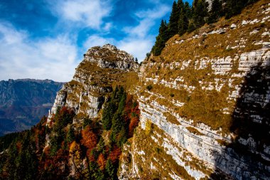 Pieve Bel Vicino Schio Vicenza Veneto İtalya 'daki sonbahar renkleriyle sarı ve yeşil ağaçların ve vadilerle dağlar arasındaki kayaların manzarası