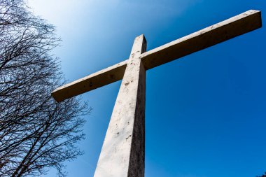 close up of a reinforced concrete cross that stands out against the cloudless blue sky in Asiago Veneto Italy