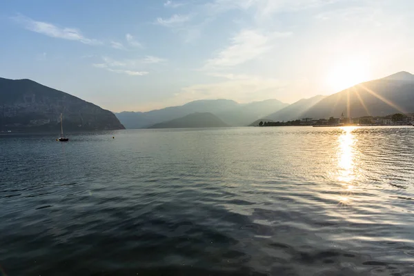sunset at lake Iseo with mountains and calm lake water reflecting Italy