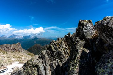 picchi di granito su cielo azzurro e nuvole bianche con valli e prati verdi facendo treckking e hiking o scalndo sulle cime Dell Lagorai a Trento Italia
