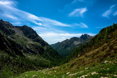 picchi di granito su cielo azzurro e nuvole bianche con valli e prati verdi facendo treckking e hiking o scalndo sulle cime Dell Lagorai a Trento Italia