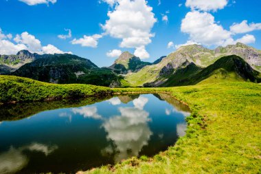 Granit dağ tepeleri, Val Campelle Trento İtalya 'sındaki Lagorai dağ sırasının zirveleri arasında yer alan küçük bir alp gölünün sakin sularına yansımaktadır.