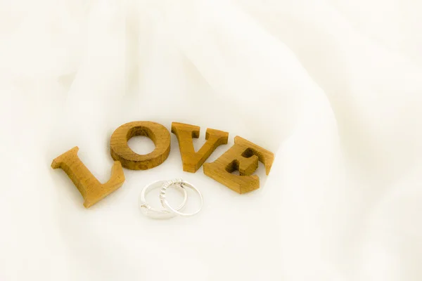 Liefde formulering en ringen op zachte witte jurk — Stockfoto