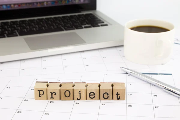 Kata-kata proyek, kalender dan laptop di tabel kantor — Stok Foto