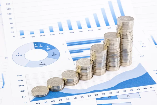 Stacks of coins on  graphs and charts — Stock Photo, Image