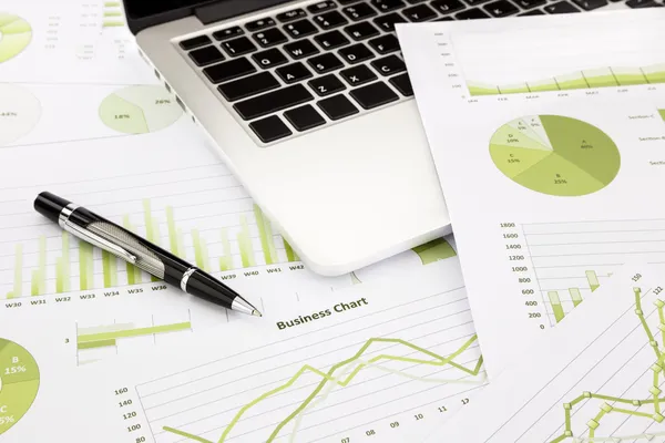 Laptop e caneta com gráficos de negócios verdes, gráficos, informações a — Fotografia de Stock