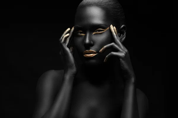 Siyaha boyanmış, altın dudaklı ve parmaklarının ucunda altın olan bir kız.