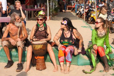 Unidentified people in carnival costumes sit, talk, play the djembe drum at the annual festival of Freaks, Arambol beach, Goa, India, February 5, 2013. clipart