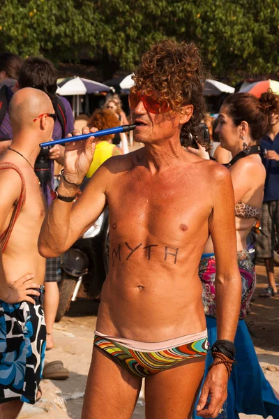 Un homme non identifié en lunettes rouges avec une inscription sur le corps jouant une pipe au festival annuel des monstres, plage d'Arambol, Goa, Inde, 5 février 2013 . — Photo