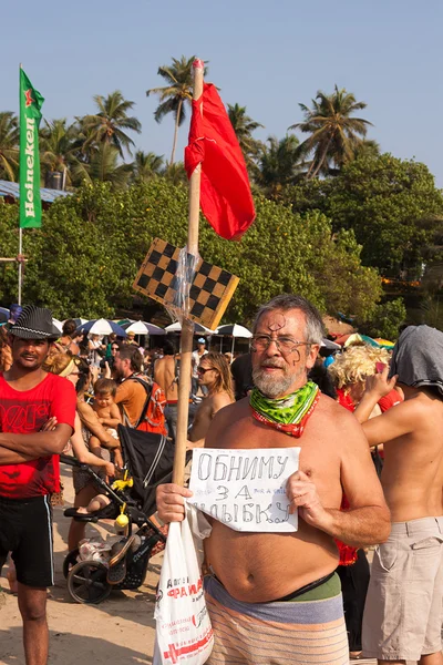 An older man with sign in his hands at the annual festival, Arambol beach, Goa, India, February 5, 2013. — Stock Photo, Image