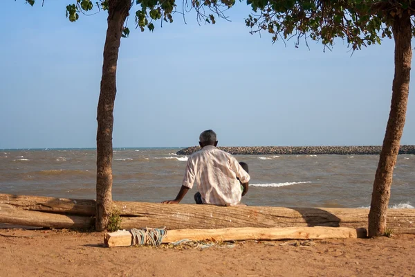 22.01.2013 - kanyakumari, tamil nadu, Hindistan. yaşlı bir adam sahilde oturuyor ve denize benziyor.