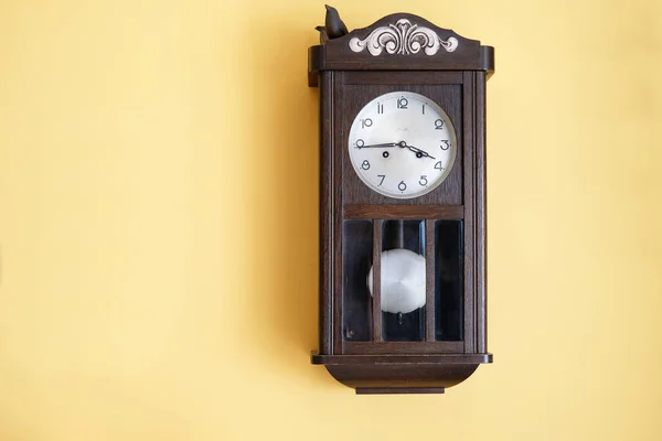 antique wooden grandfather\'s clock on yellow wall
