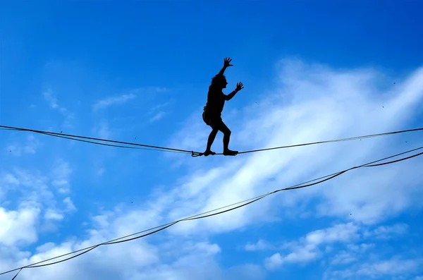 Lublin, Poland 29 July 2022. Silhouette of a young man walking on a tightrope against blue sky at Urban Highline Festival