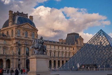 Günbatımında ünlü Louvre Müzesi ve cam piramit manzarası. Dünya çapında en çok ziyaret edilen müze ve Paris, Fransa 'nın başlıca turistik merkezlerinden biri.