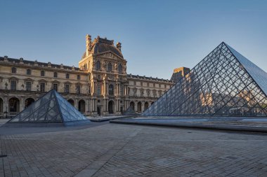 Ünlü Louvre Müzesi manzarası ve güneş doğarken cam piramit. Dünya çapında en çok ziyaret edilen müze ve Paris, Fransa 'nın başlıca turistik merkezlerinden biri.