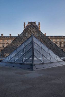 Ünlü Louvre Müzesi manzarası ve güneş doğarken cam piramit. Dünya çapında en çok ziyaret edilen müze ve Paris, Fransa 'nın başlıca turistik merkezlerinden biri.