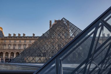 Ünlü Louvre Müzesi manzarası ve güneş doğarken cam piramit. Dünya çapında en çok ziyaret edilen müze ve Paris, Fransa 'nın başlıca turistik merkezlerinden biri.