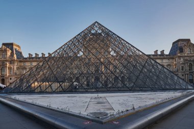 Ünlü Louvre Müzesi manzarası ve güneş doğarken cam piramit. Dünya çapında en çok ziyaret edilen müze ve Paris, Fransa 'nın başlıca turistik merkezlerinden biri.