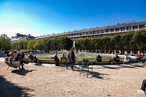 法国巴黎皇家宫花园的水泉旁 人们正享受着宜人的天气 — 图库照片