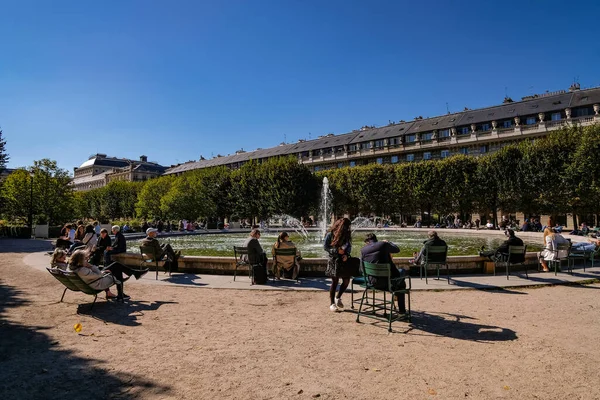 法国巴黎皇家宫花园的水泉旁 人们正享受着宜人的天气 — 图库照片