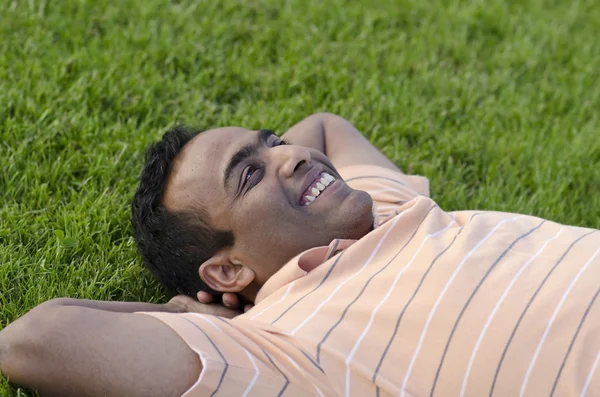 Man relaxing outdoors looking happy and smiling — Stock Photo, Image