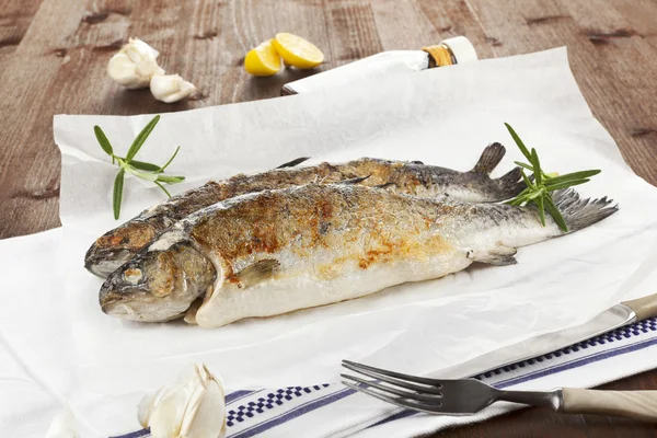 Two grilled trouts with fresh herbs and lemon pieces on wooden t — Stock Photo, Image