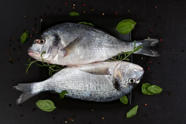 Zwei Fische auf schwarzem Teller, Draufsicht. — Stockfoto