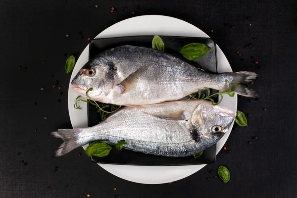 Two fish with fresh herbs on plate, top view. — Stock Photo, Image
