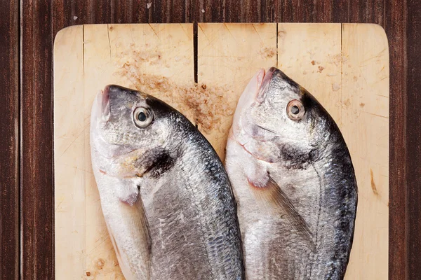 Dwie ryby na drewnianą deską do krojenia. — Zdjęcie stockowe