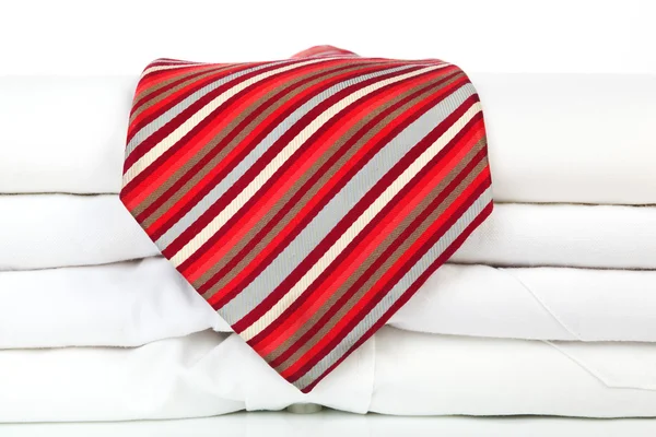 Stapel weißer Hemden mit roter Krawatte. — Stockfoto