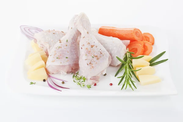 Kuřecí stehna s čerstvou zeleninou, které jsou uspořádány na bílý talíř. — Stock fotografie
