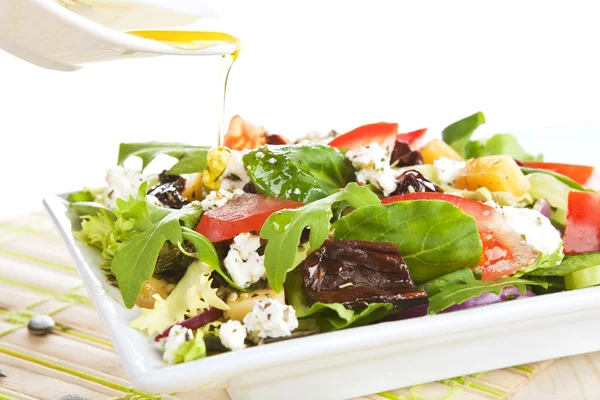 Gieten van olijfolie op verse salade. — Stockfoto