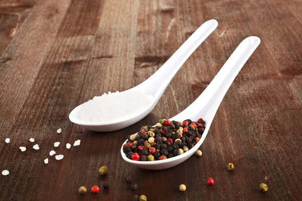 Salt and pepper on white spoons. — Stock Photo, Image