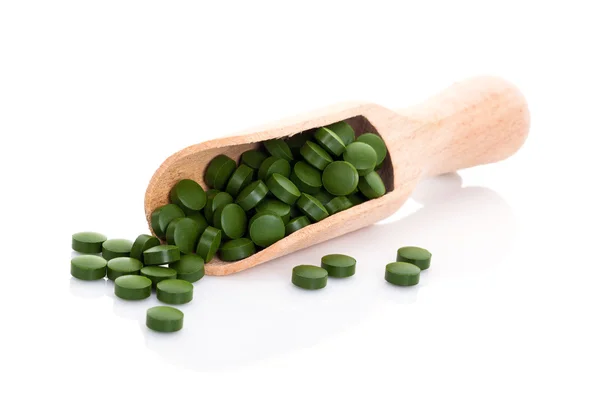 Pastillas (tabletas) de vitaminas, suplementos dietéticos o medicamentos para el estómago en cuchara de madera, aisladas en blanco — Foto de Stock