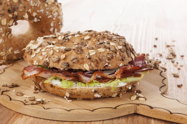 Whole grain bagel with bacon. — Stock Photo, Image