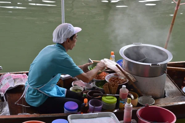 Hombre cocinando en barco al mercado flotante Imágenes De Stock Sin Royalties Gratis