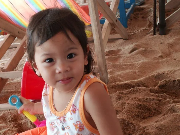 Uma menina sentada na areia com sorriso no rosto — Fotografia de Stock