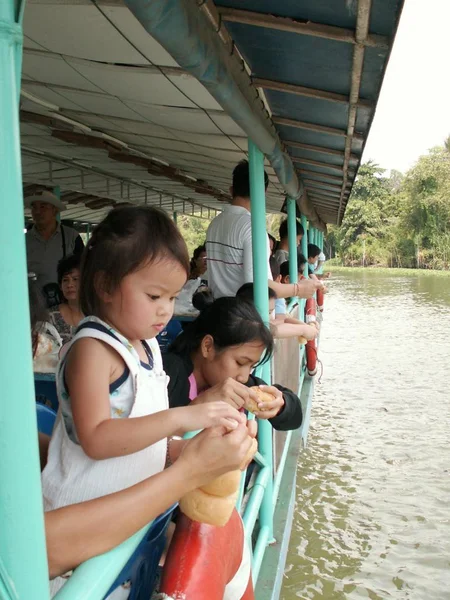 Little girl feeding some bread for fish in Chao-phraya river , Bangkok Thailand — Fotografie, imagine de stoc