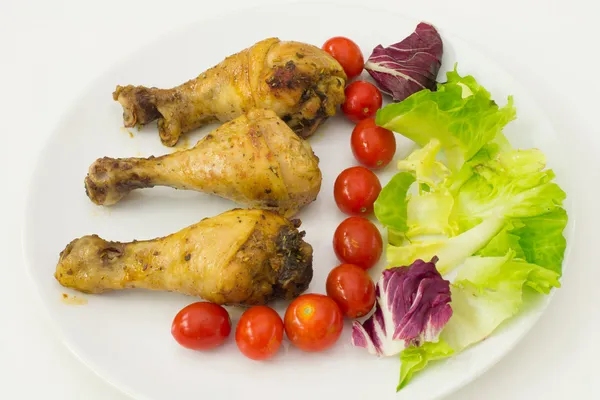 Hühnerkeulen mit Tomaten und Salat lizenzfreie Stockfotos