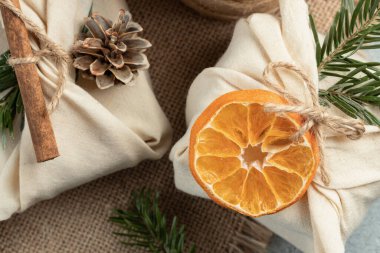 Sıfır israf noeli konsepti. Doğal kumaş hediyeleri ve doğal malzemelerle doldurulmuş gri masa, yakın plan, üst manzara