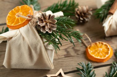 Sıfır israf noeli konsepti. Doğal kumaş hediyeleri ve doğal malzemelerle ahşap bir masa üzerinde paketlenmiş.