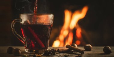 Yanan şöminenin yanında sıcak şaraplı cam bardak.
