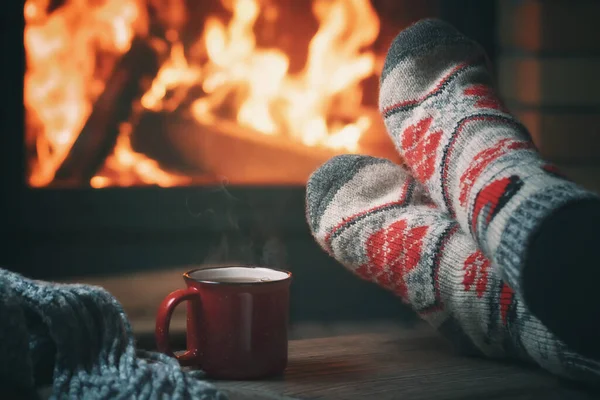 Mädchen, das an einem Winterabend an einem brennenden Kamin in einem Landhaus ruht und sich die Füße wärmt. Selektiver Fokus — Stockfoto