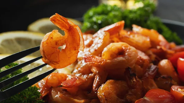 Los langostinos fritos sobre el tenedor el primer plano sobre el fondo de los langostinos y la verdura en el plato —  Fotos de Stock