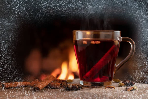 Glass mug with hot mulled wine by the burning fireplace — Stock Photo, Image