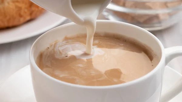 Milch oder Sahne in frisch gebrühten Kaffee gießen, aus nächster Nähe — Stockfoto
