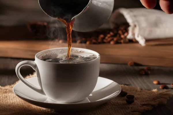 Verter café cezve caliente recién hecho en una taza blanca Fotos De Stock