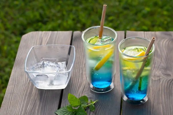 Два келихи з літнім прохолодним синім лагунним коктейлем на дерев'яному столі. Вибірковий фокус — стокове фото