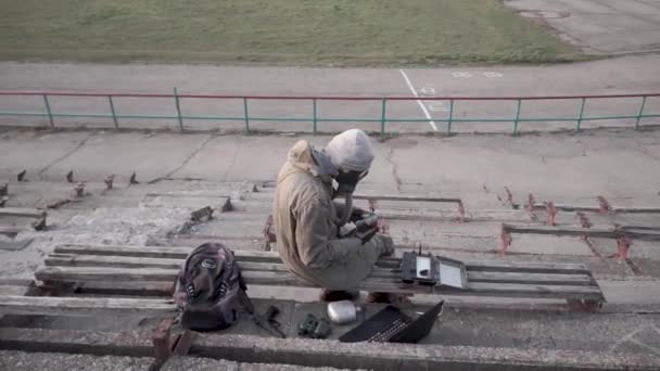 Ein Mann Mit Gasmaske Beim Essen Auf Einem Zerstörten Platz — Stockvideo