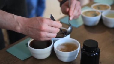 barista and woman's hands with cup of coffee and other tea in wooden box on kitchen chair